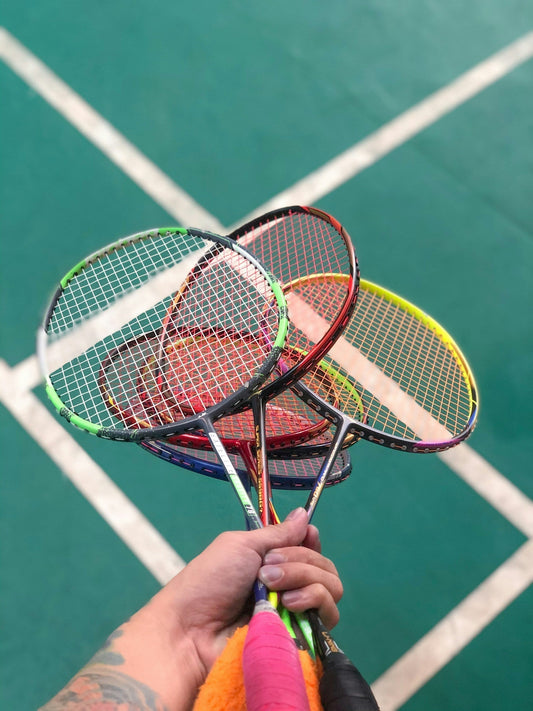 Player comparing two Yonex badminton racquets to choose the right one for their skill level and playing style