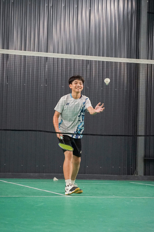 Beginner badminton player learning to play on an indoor court in Australia — getting started with the basics