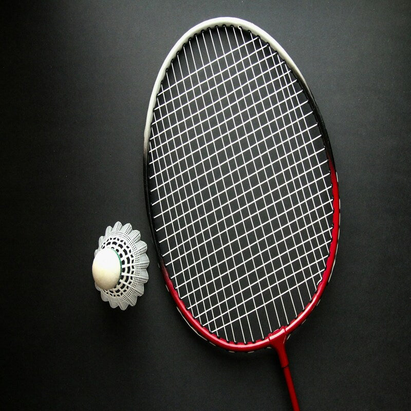 Intermediate badminton player mid-rally on indoor court — upgrade to graphite Yonex racquets for club players